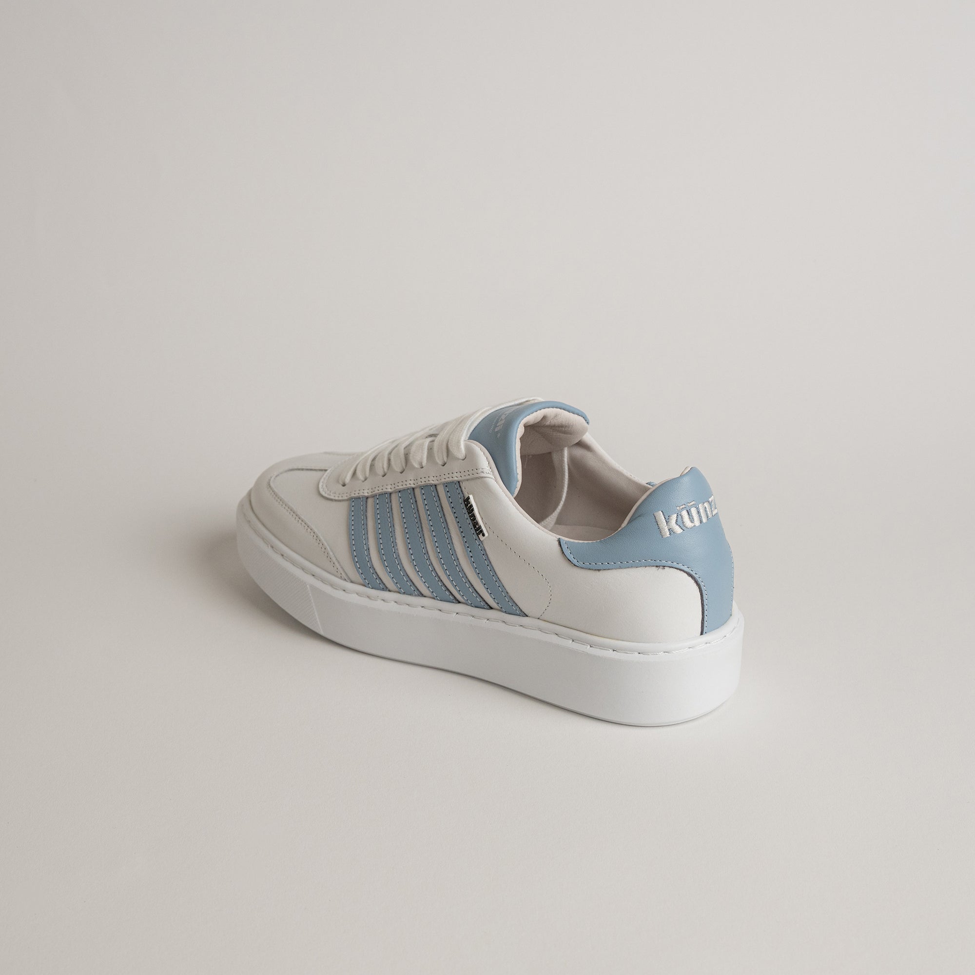 Ein weiß-blauer Sneaker von Kuenzli Schuhe aus Leder auf hellem Hintergrund.