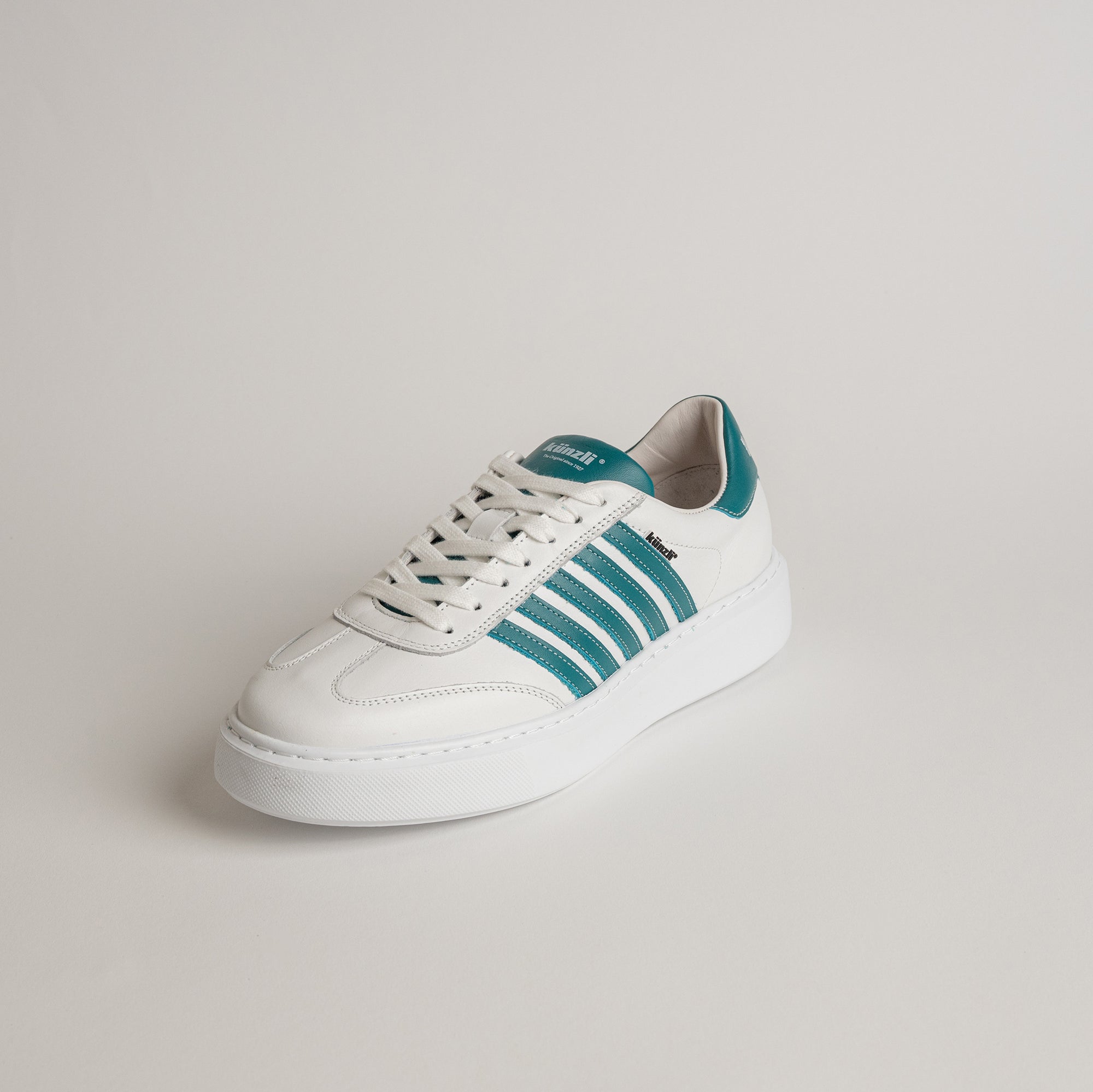 Weißer Kuenzli Schuh mit grünen Streifen auf hellem Hintergrund, ideal für Freizeitaktivitäten.