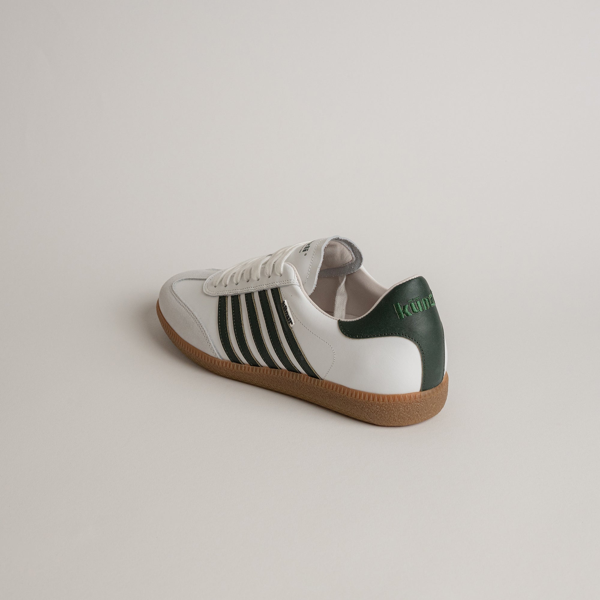 Weißer Kuenzli Schuh mit grünen Details und Gummisohle auf hellem Hintergrund.