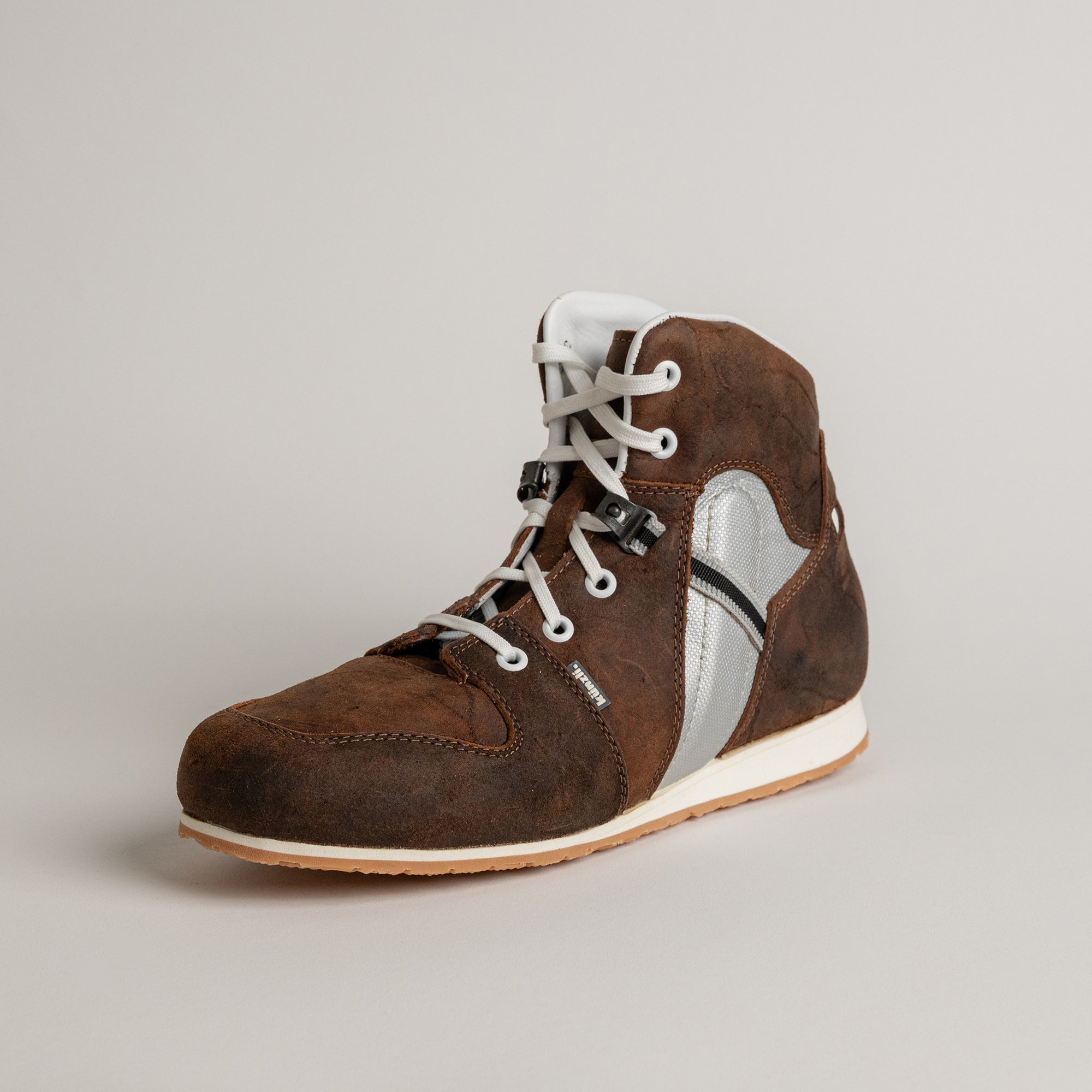 Brauner Kuenzli Schuh aus Leder mit weißem Schnürsenkel auf grauem Hintergrund.
