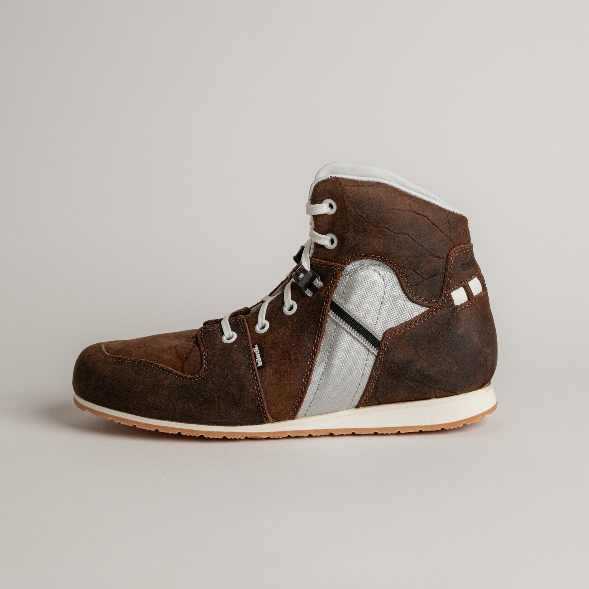 Ein brauner Lederschuh von Kuenzli Schuhe mit weißer Sohle und Schnürsenkeln.