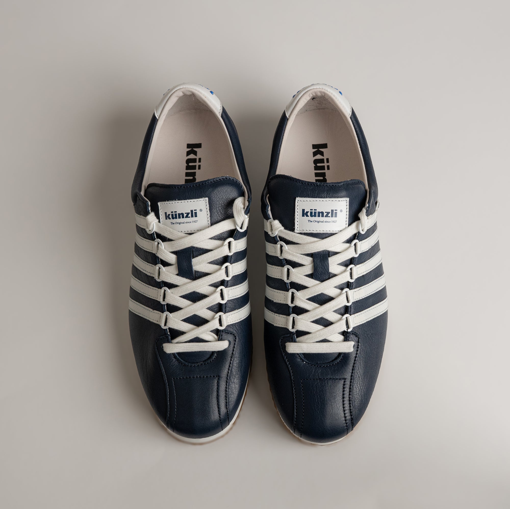 Schwarze Kuenzli Schuhe mit weißen Streifen und Schnürsenkeln auf hellem Hintergrund.