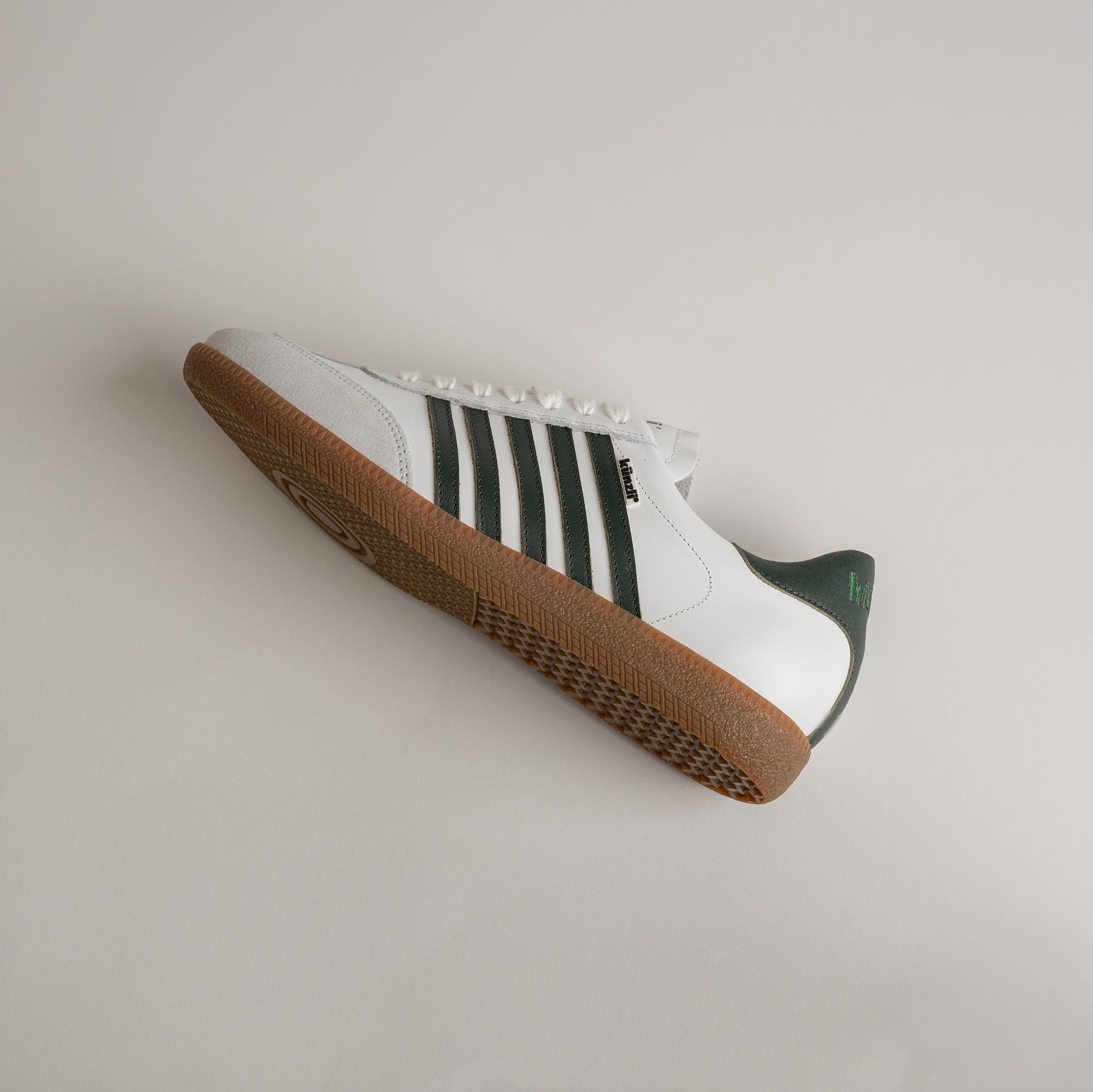 Weißer Kuenzli Schuh mit grünen Streifen und brauner Sohle auf hellem Hintergrund.