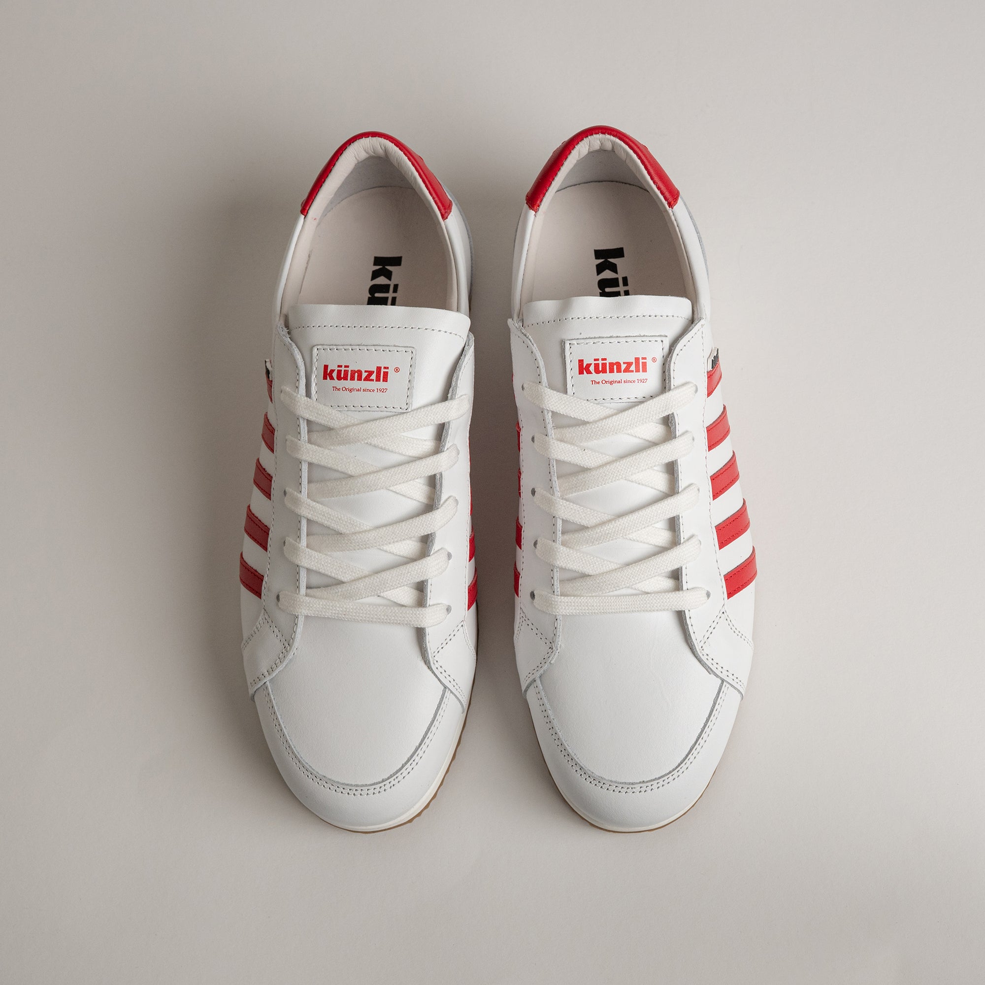 Weiße Kuenzli Schuhe mit roten Streifen, ideal für sportliche Aktivitäten und Freizeit.