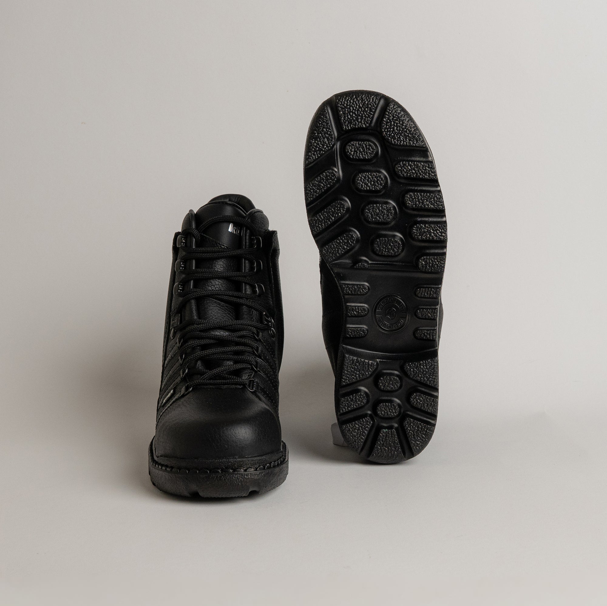 Schwarze Lederstiefel von Kuenzli Schuhe mit robuster Profilsohle auf grauem Hintergrund.