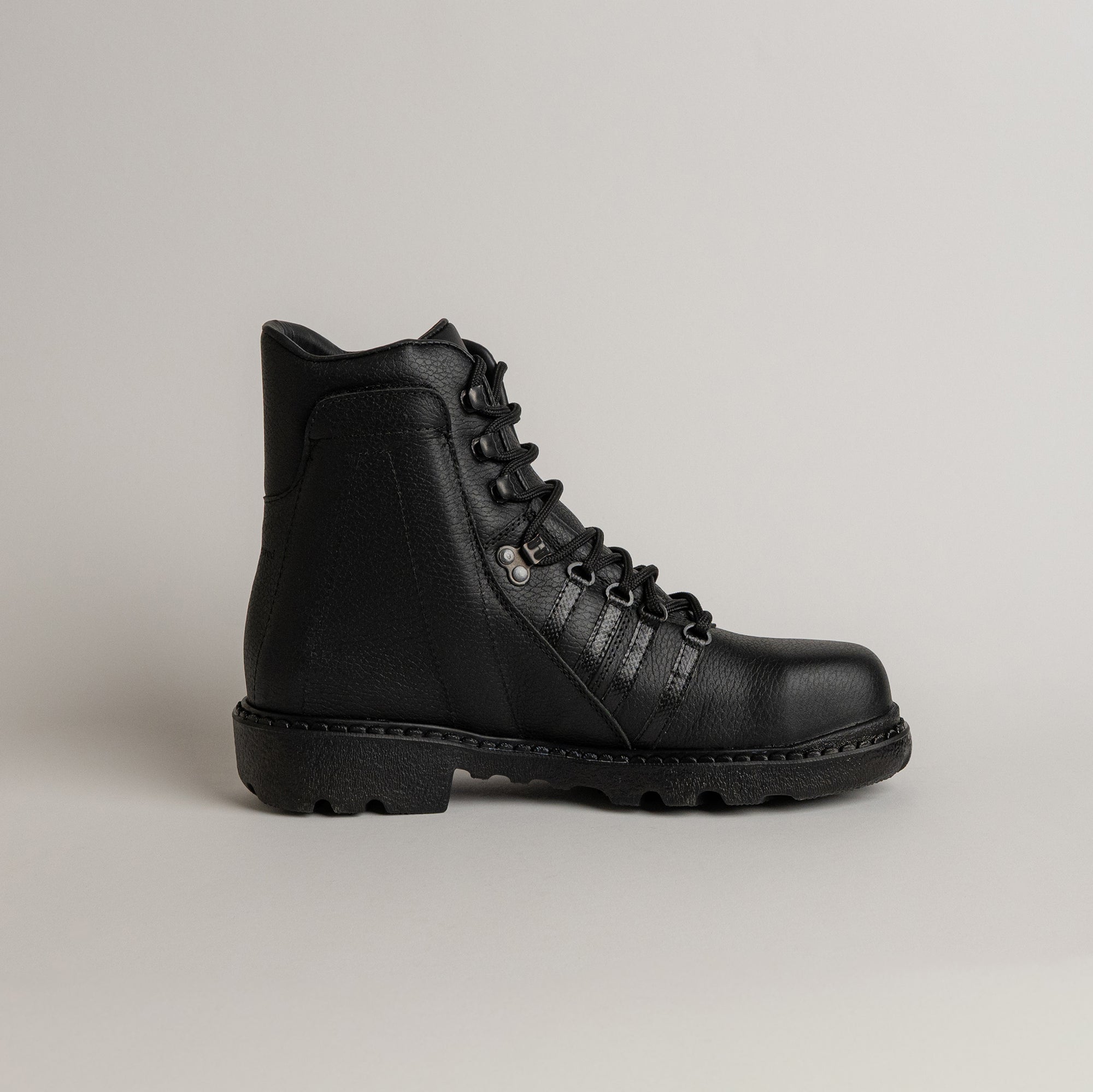 Schwarzer Lederstiefel von Kuenzli Schuhe mit robuster Sohle auf grauem Hintergrund.