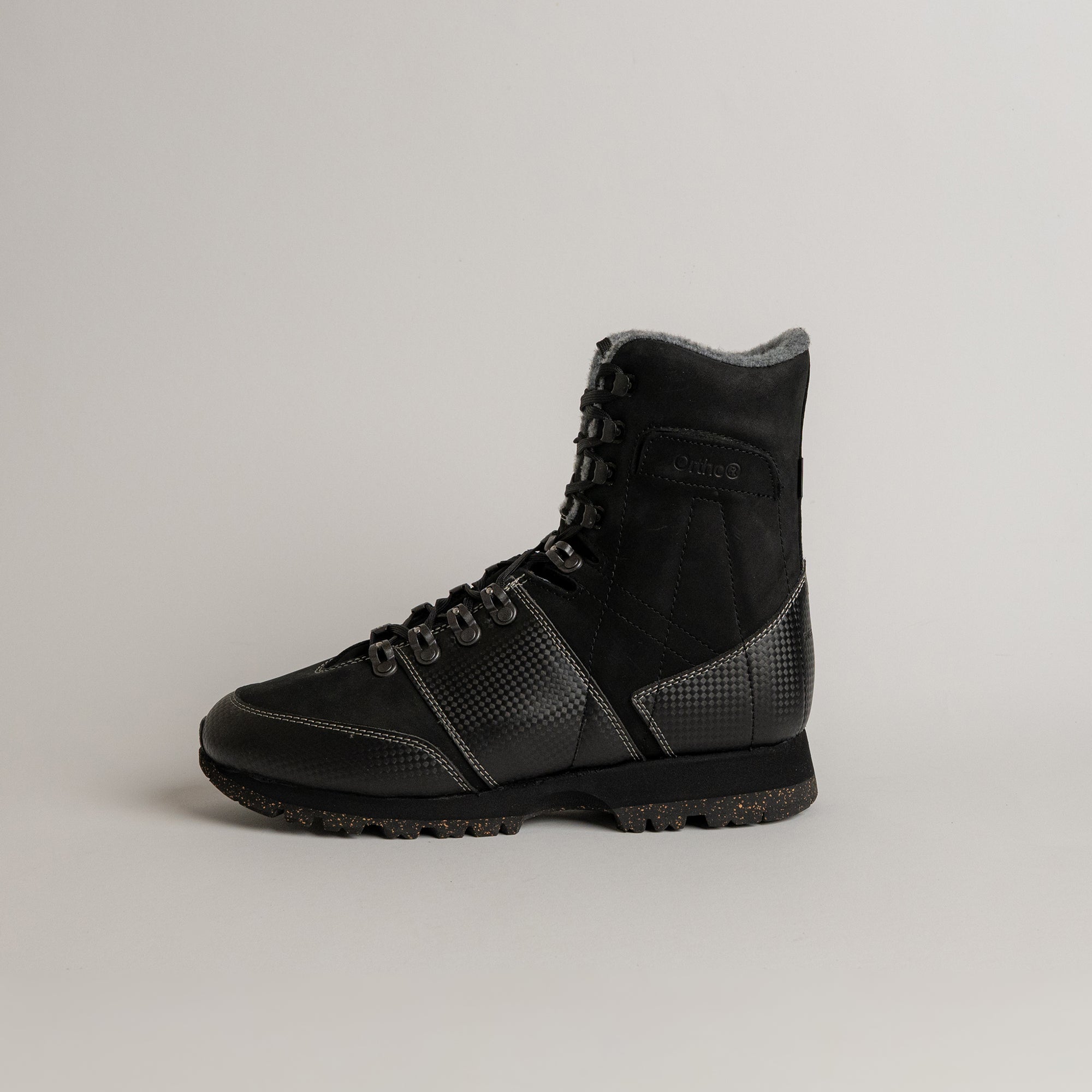 Schwarzer Lederstiefel von Kuenzli Schuhe mit robustem Profil auf grauem Hintergrund.