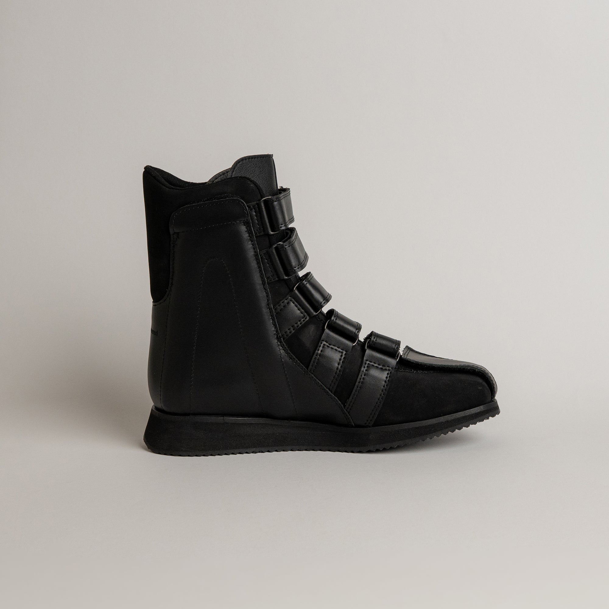 Schwarzer Lederstiefel von Kuenzli Schuhe mit mehreren Schnallen auf hellem Hintergrund.