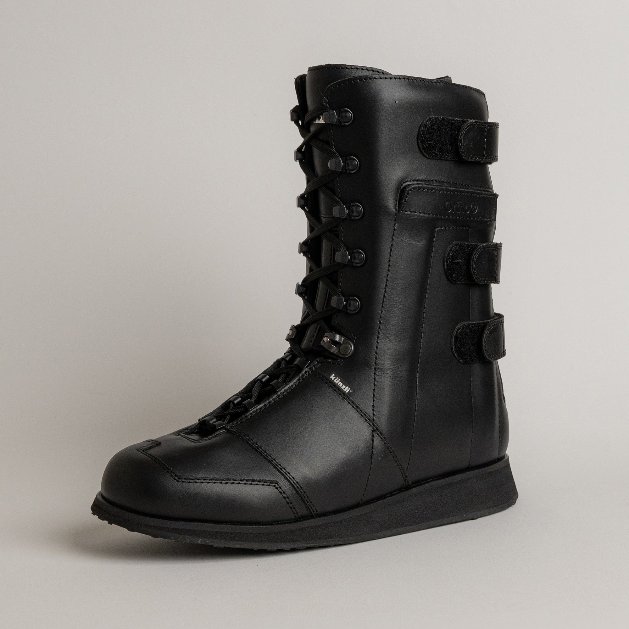 Schwarzer Lederstiefel von Kuenzli Schuhe mit Schnürung und Klettverschlüssen, seitlich fotografiert.