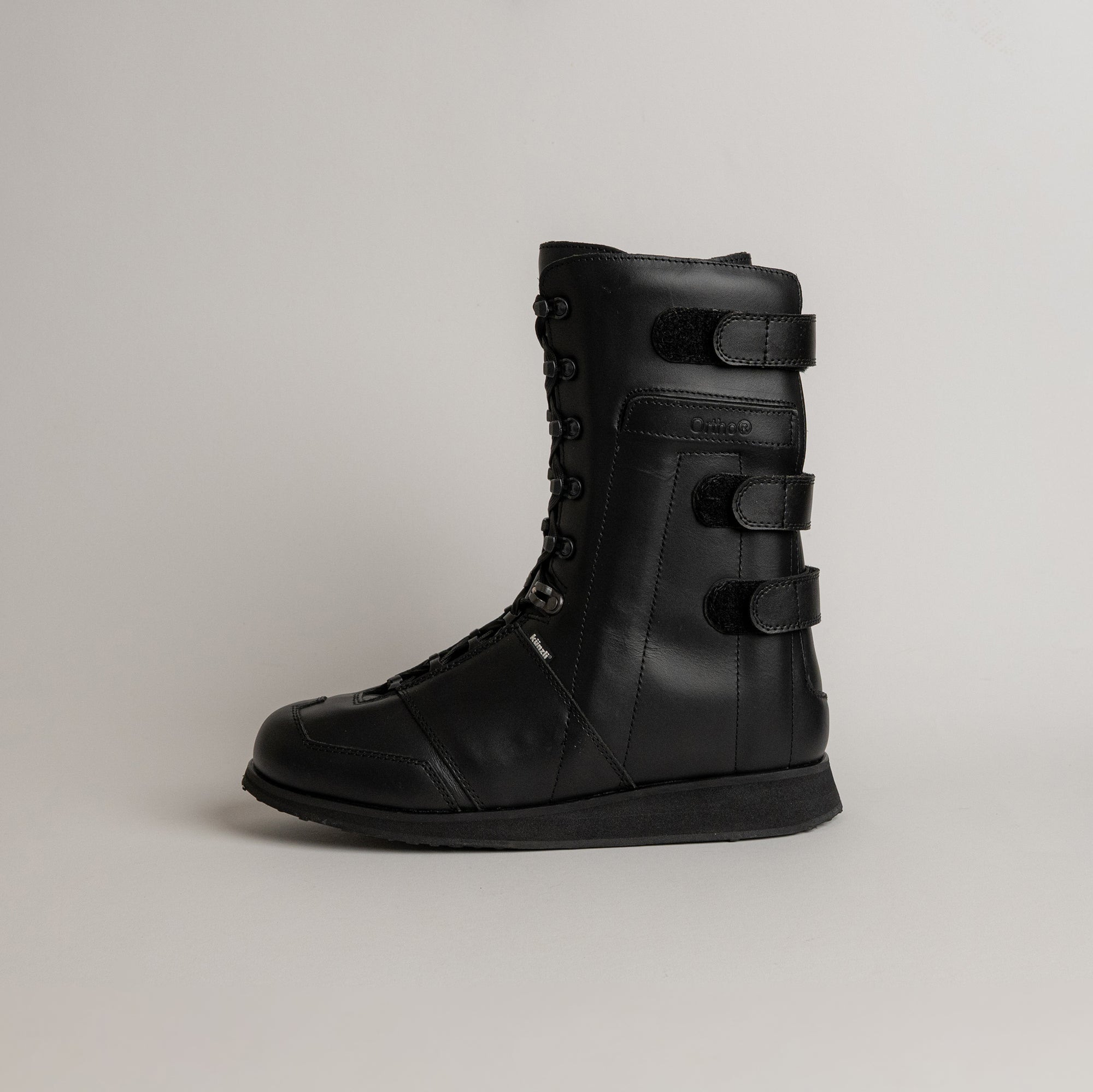 Schwarzer Lederstiefel von Kuenzli Schuhe mit Schnürung und Klettverschluss, seitlich fotografiert.