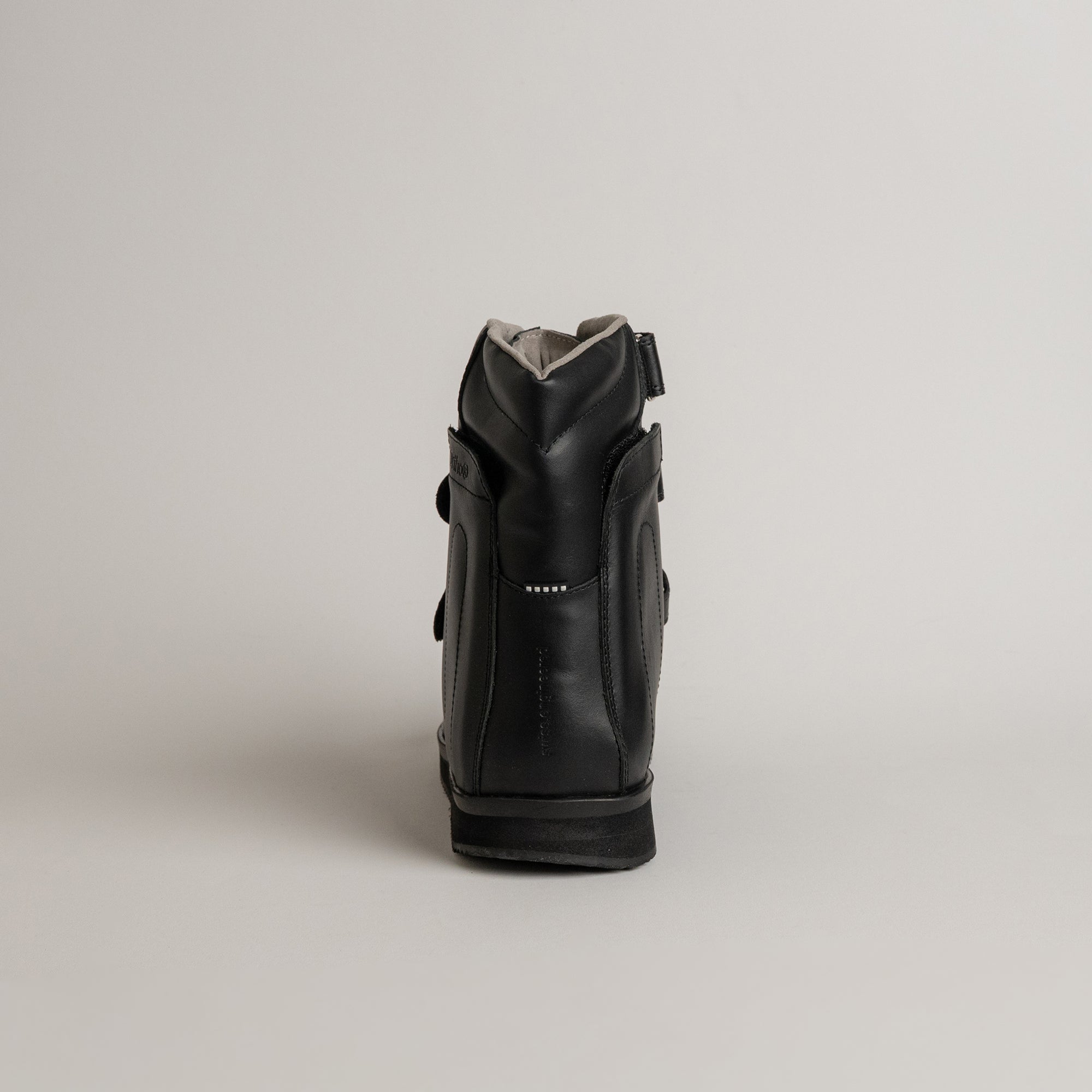 Schwarzer Lederstiefel von Kuenzli Schuhe, seitlich fotografiert, auf grauem Hintergrund.