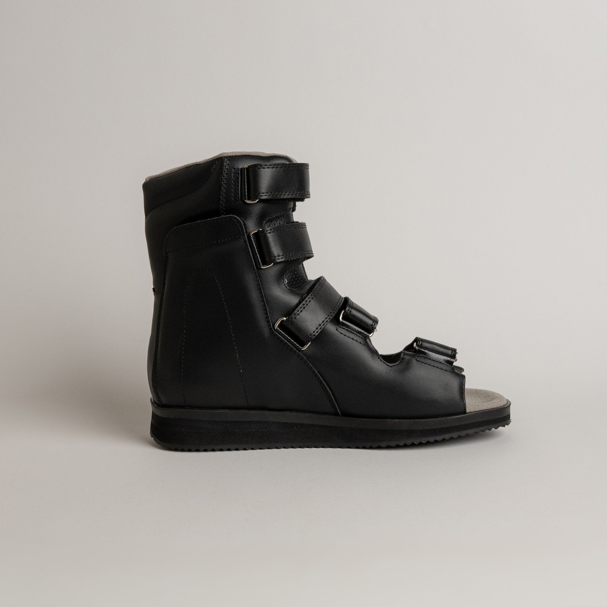 Schwarzer orthopädischer Schuh von Kuenzli Schuhe mit Klettverschlüssen auf grauem Hintergrund.
