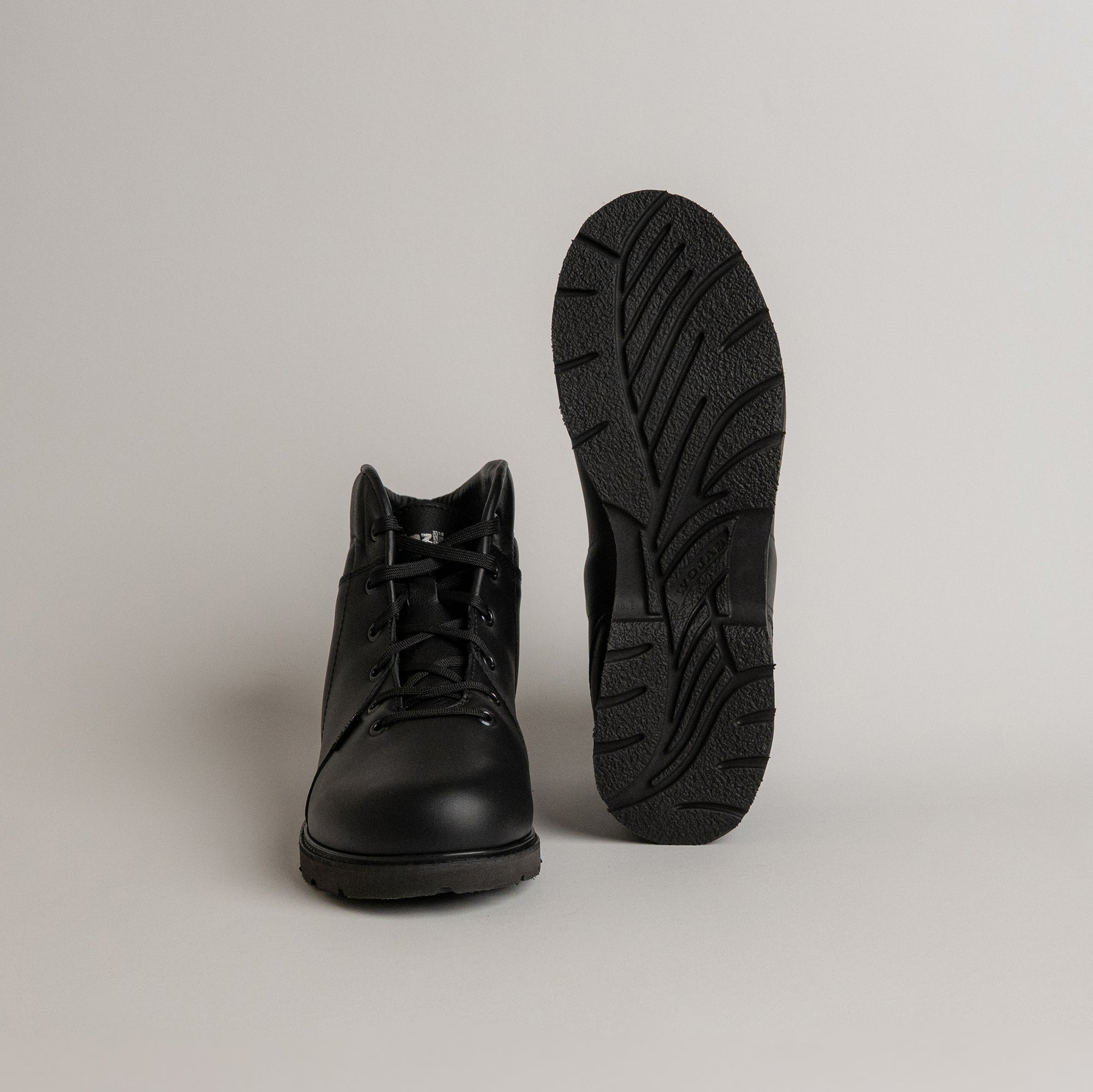 Schwarze Kuenzli Schuhe aus Leder mit robustem Profil auf grauem Hintergrund.