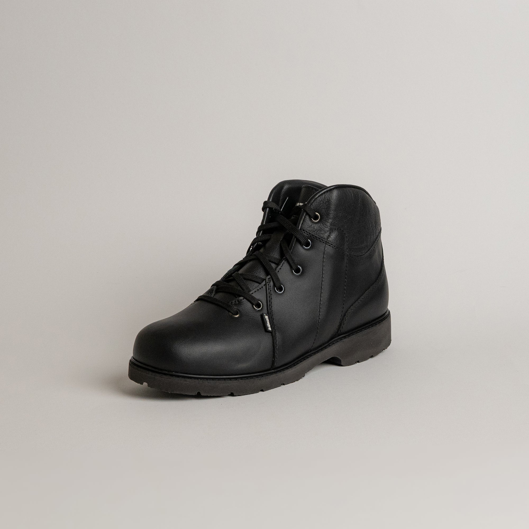 Schwarzer Lederstiefel von Kuenzli Schuhe auf grauem Hintergrund, ideal für Outdoor-Aktivitäten.