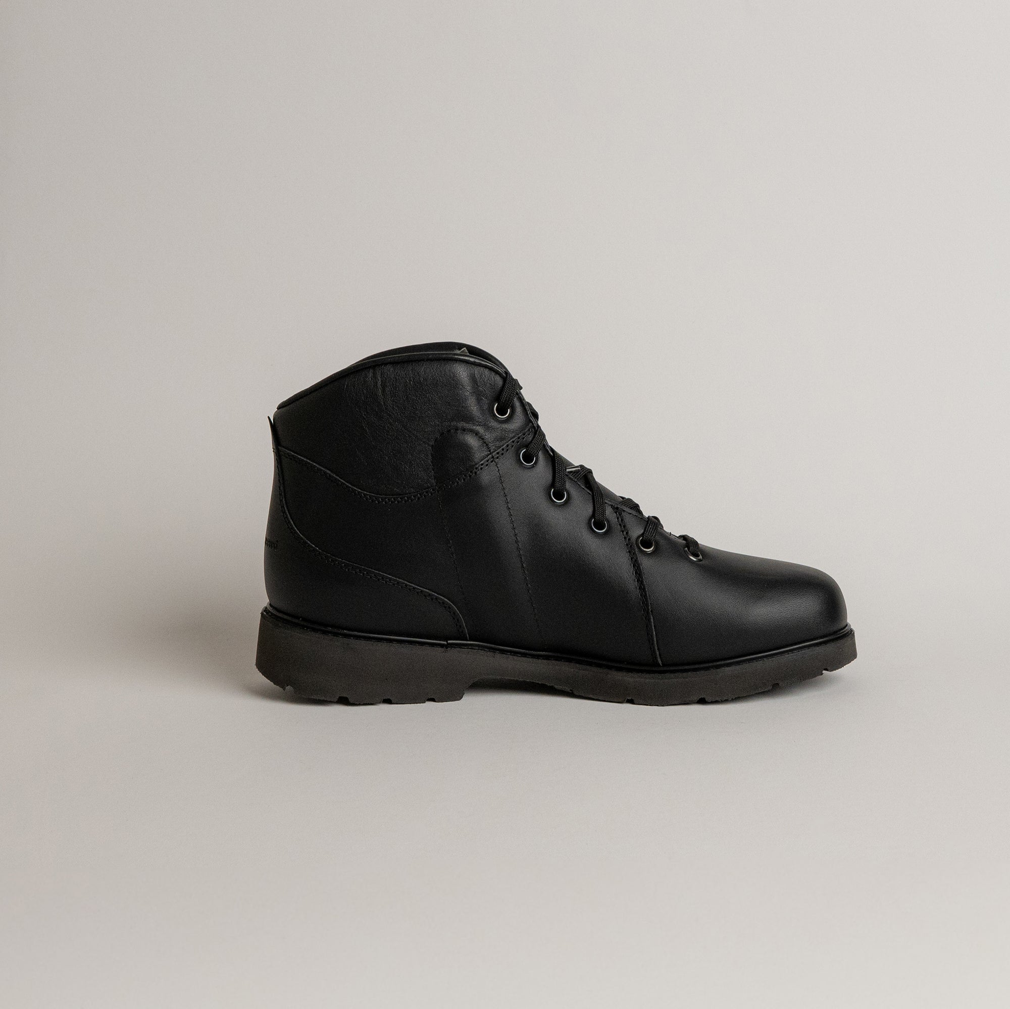 Schwarzer Lederstiefel von Kuenzli Schuhe auf grauem Hintergrund, ideal für Outdoor-Aktivitäten.