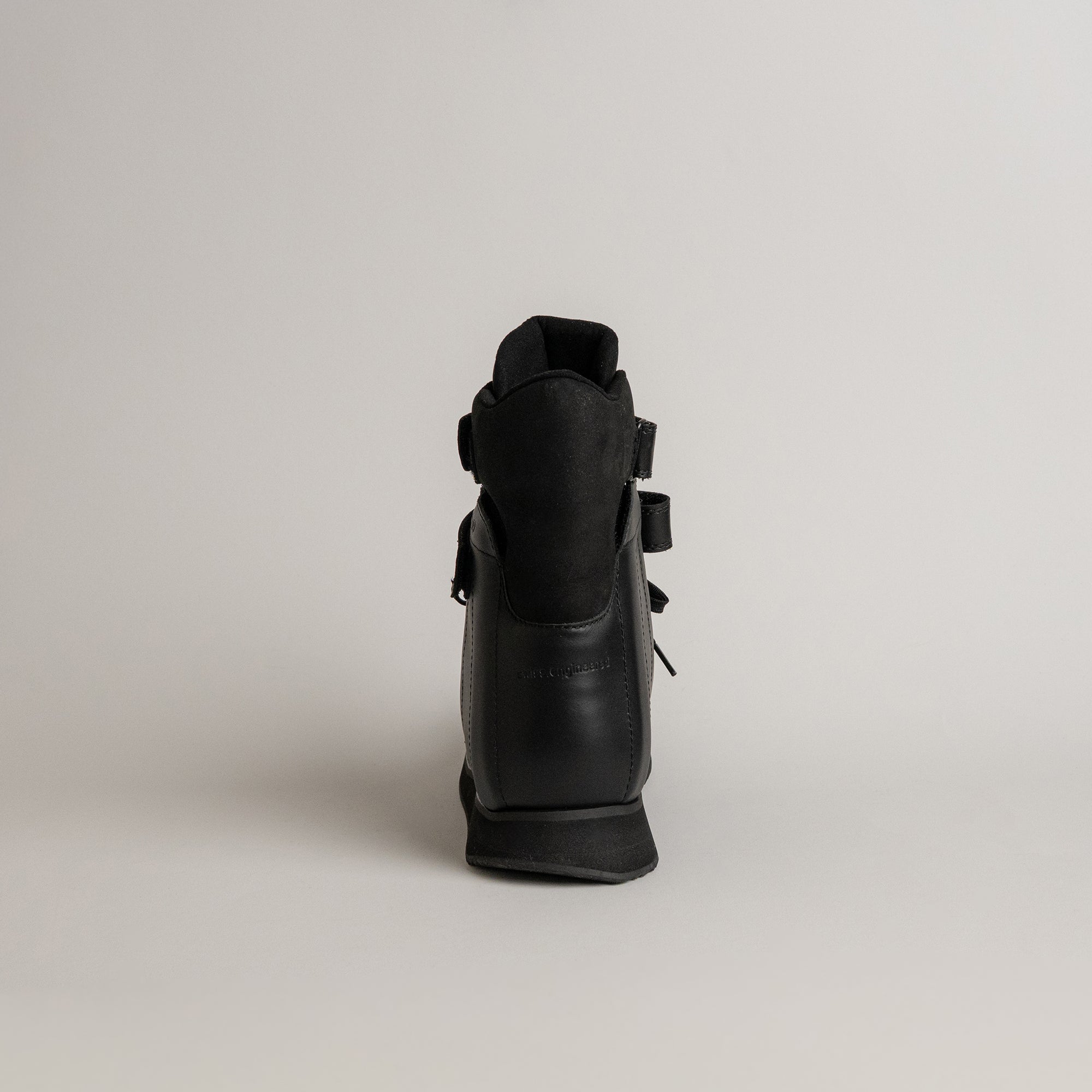 Schwarzer Kuenzli Schuh aus Leder, von hinten fotografiert, auf grauem Hintergrund.