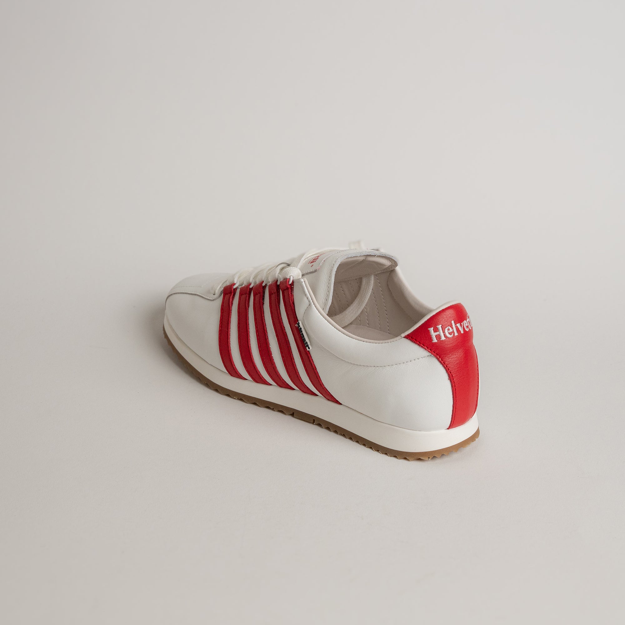 Weißer Sneaker mit roten Streifen von Kuenzli Schuhe auf hellem Hintergrund.
