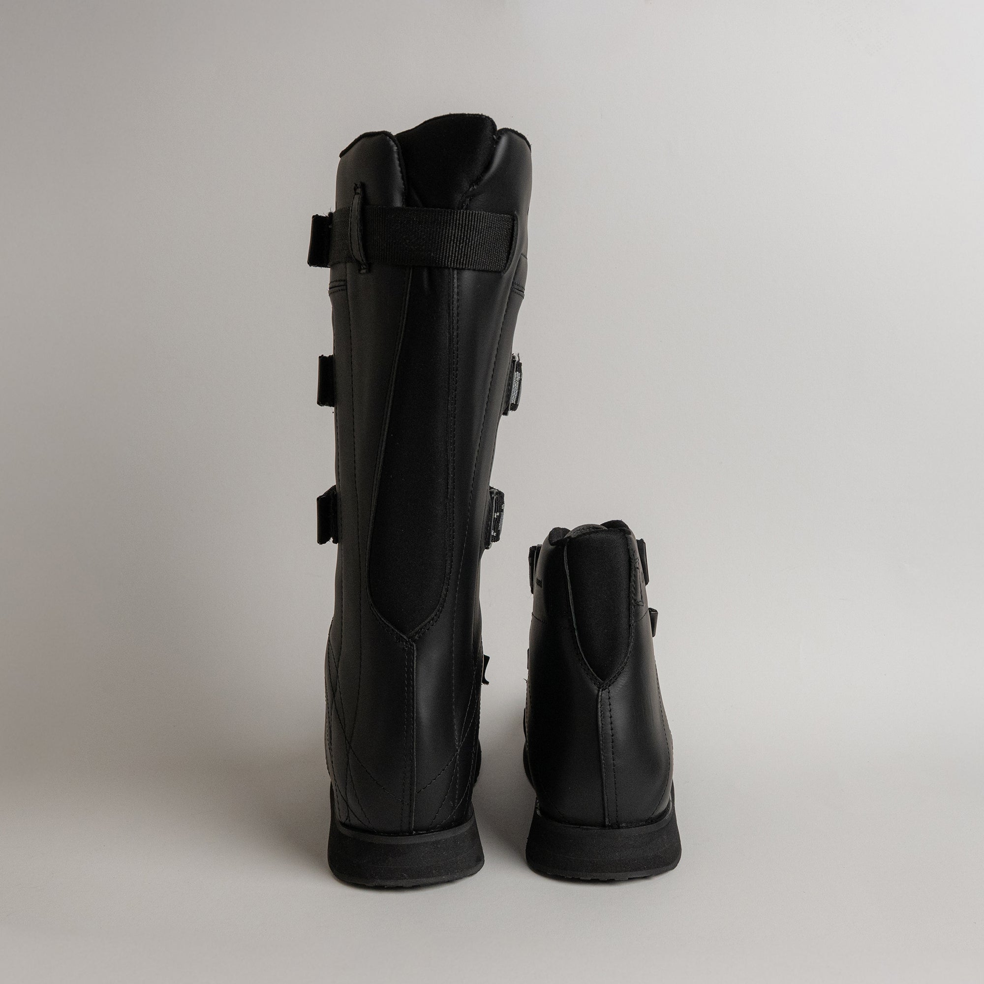 Schwarze Lederstiefel von Kuenzli Schuhe, ideal für Outdoor-Aktivitäten, auf grauem Hintergrund.